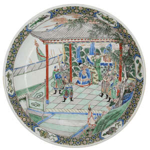 A Chinese porcelain dish, late 19th century, painted in famille verte enamels with an official with guards and attendants beneath a pagoda, underglaze blue apo