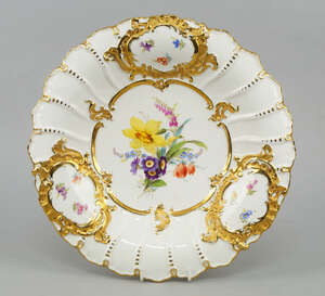 A Meissen porcelain plate, late 19th/early 20th century, painted with flowers to the central well, with three reserves of flower sprays to the rim, in raised g