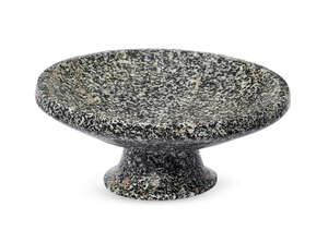 An Achaemenid granite footed bowl, circa 5th century B.C., the thick tapering foot splayed at the base, hollowed on the underside, the shallow bowl with broad 