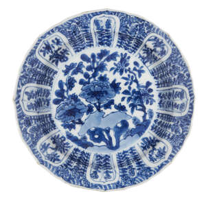A Chinese porcelain dish, Kangxi period, painted in underglaze blue with flowering peony blooms to the central reserve, the border decorated with panels of flo