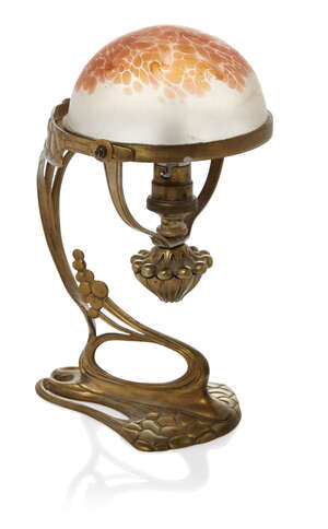 
	
		An Art Nouveau bronze table lamp with Loetz glass shade  
		c.1900  
		The small domed...