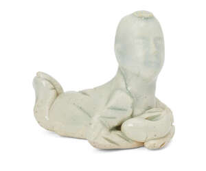 A Chinese porcelain qingbai brush rest, Song dynasty, modelled as a young child lying on its stomach with head and feet crossed, the child is dressed in a long