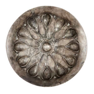 An Achaemenid silver phiale, circa 5th-4th century B.C., the shallow bowl with everted rim, decorated with twelve lotus buds around a central raised bosse, 28c