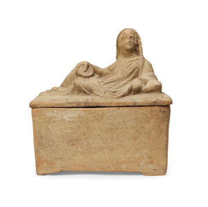 An Etruscan terracotta cinerary urn and lid, circa 3rd-1st Century B.C., the lid in the form of the figure of the deceased, reclining and draped in a himation,