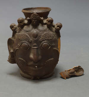 
	
		A large Nepalese terracotta jar, 20th century, formed as a Bhairava mask adorned with...
