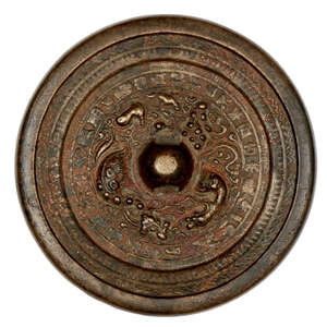 
	
		A Chinese bronze 'lion and grapes' circular mirror, Tang dynasty, the central knob...