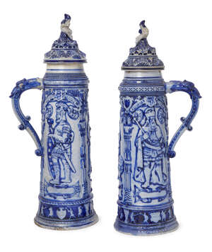 
	
		A pair of 19th century German blue tall steins, lids with figural finials, the bodies...