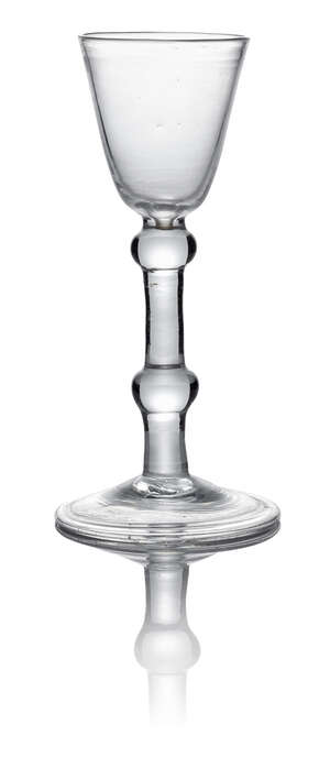 A George II balustroid wine glass, c. 1740, with round funnel bowl above shoulder and medial knops on conical folded knop foot, 15.5cm high