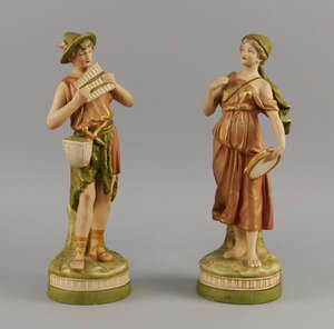A pair of Royal Dux porcelain figures of an Alpine boy and girl, late 19th/early 20th century, he playing pan pipes and she holding a tambourine, modelled on n