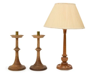 A pair of turned oak candlesticks, in the Arts & Crafts manner, 20th century, each with brass nozzle, 35cm high; together with a turned oak table lamp, with pl
