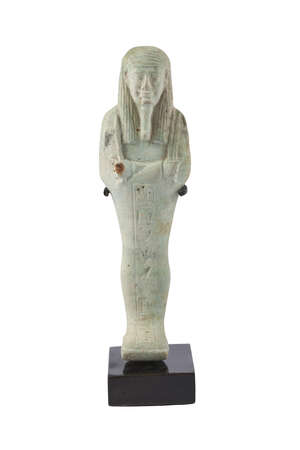 
	
		An Egyptian green-glazed faience shabti, wearing a tripartite striated wig and false...