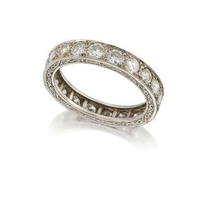 A platinum, diamond eternity ring, set with a single row of circular-cut diamonds the hoop with foliate engraved sides, circa 1930, ring size N