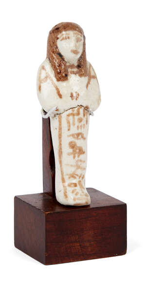 
	
		An Egyptian white-glazed composition shabti, 19th-20th Dynasty, modelled with crossed...