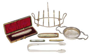 
	
		A small group of silver items comprising: a navette-shaped toast rack raised on four ball...