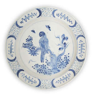 
	
		A Delft charger, 18th century, painted with a parrot perched on a branch, the border with...