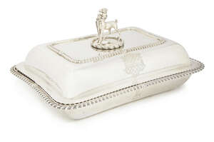 A George III silver entree dish and cover, London c.1819, William Eaton, with concave sides and gadrooned rims, the cover engraved with crests and surmounted b