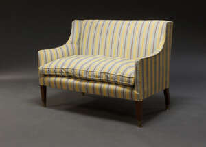 
	
		An Edwardian sofa, upholstered in yellow striped fabric, with loose seat cushion, raised...