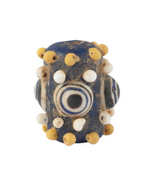 An 'Eye' Bead, Phoenician, 7th-6th century BC, of tubular form, with yellow and white smaller protrusions, 2.7cm. high
		 
		Provenance: Private col