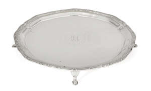 A silver card tray, Chester, c.1919, Barker Brothers, of rounded form and raised on four hoof feet, the base decorated with monogram and garland engraving to r