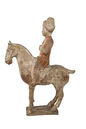 A Chinese pottery figure of a horse and rider, Tang dynasty, with traces of painted decoration to the rider, the horse standing on rectangular base, 34cm high