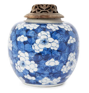 A Chinese porcelain ginger jar, Kangxi period, painted in underglaze blue with prunus blossom on a cracked ice ground, unmarked, 15cm high, pierced wood cover