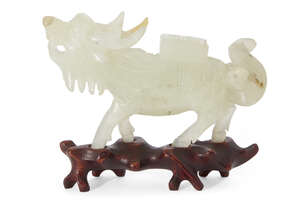 A Chinese bowenite kylin, early 20th century, carved striding forward carrying a book of...