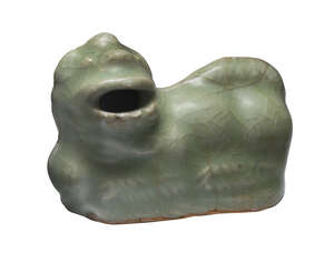 A Chinese Longquan celadon waterdropper, Ming dynasty, modelled as a recumbent Buddhist lion, 7cm long