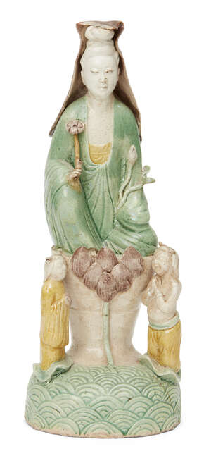A Chinese biscuit porcelain sancai Guanyin figure group, Kangxi period, modelled as Guanyin seated on a raised lotus throne holding a ruyi sceptre and a flower