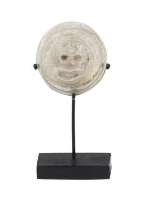 A Roman glass theatre token depicting a theatre mask, 1st-3rd century AD, on stand, 3cm. diam. 
		 
		Provenance: Collection of George and Dora Mathues, Phi