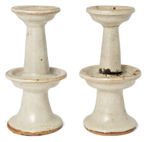 A pair of Chinese stoneware candlesticks, late Yuan/ early Ming dynasty, of two-tiered circular form, covered in a pale Qingbai glaze, 15.5cm high