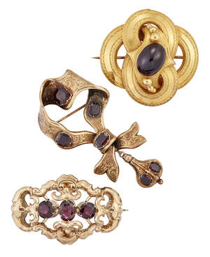 Three Victorian gold and garnet brooches, comprising: one of looped quatrefoil design with central closed-set oval cabochon ruby and bead detail, width 4.5cm; 