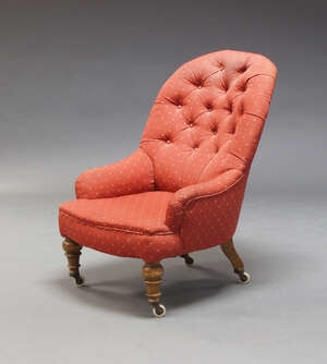 
	
		A Victorian button back nursing chair, upholstered in red fabric, on turned front legs...