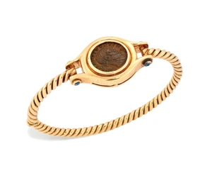 A reproduction coin set bangle, designed as a reproduction Roman coin in spectacle mount with...