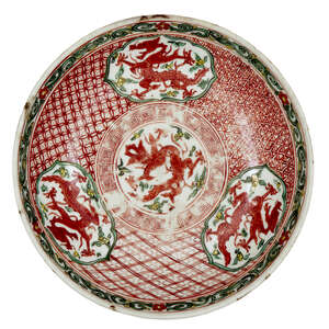 A Chinese porcelain wucai saucer dish, late Ming dynasty, 17th century, painted with three panels of dragons around a central dragon medallion, unmarked, 17.5c