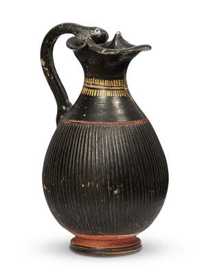 An Etruscan red and black glazed pottery jug with serpent head handle, circa 6th century B.C., with ribbed body, 19.5cm. 
		Provenance: Property of a Lady