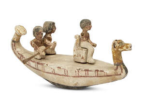 An Egyptian gesso-painted wood funerary model of a boat, Middle Kingdom, circa 2046-1794 B.C., the boat manned by two oarsmen, with seated figure to bow, 43cm.