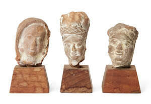 
	
		Three small sandstone carved heads, Gupta period, India, 3rd-4th century AD, on wood...