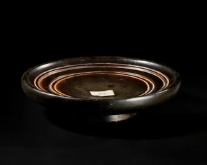 A Greek black-glazed pottery plateSouth Italy, Circa 4th century BC
A footed plate with a deep,...