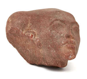 
	
		An Egyptian style red sandstone head of an Amarna style princess, with elongated skull...
