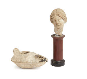 
	
		An Ancient fragmentary terracotta head of a woman, hear hair in braids, with an elongated...