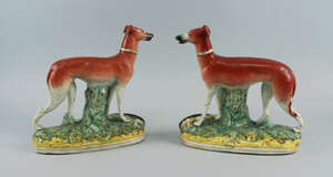 A pair of Staffordshire greyhounds, 19th century, modelled standing on oval naturally modelled bases with ferns and tree stumps, each with a rabbit at its feet