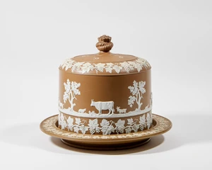 A brown jasperware cheese dome, probably James Dudson, c.1870-80, unmarked, with knotted rope finial and five air holes, the cover decorated in raised white re
