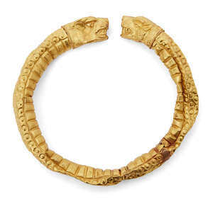 A reproduction Greek style gold bracelet, hollow with lion head terminals, with incised details for the fur, 7.2cm diam., 13.6 grams.
		 