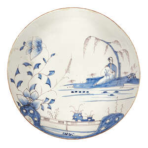 
	
		A Delft Chinoiserie charger, early 19th century, decorated with a river landscape with a...