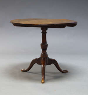 
	
		A George III mahogany tilt top table, on turned baluster support to tripod legs and pad...