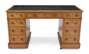 A Victorian oak pedestal desk, third quarter 19th century, the tooled green leather writing surface above an arrangement of nine drawers, on plinth bases and 