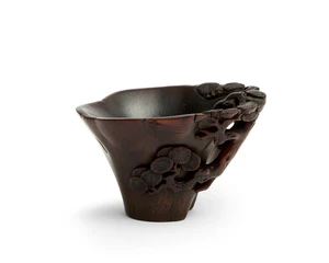 A Chinese rhinoceros horn ‘pine tree’ libation cup
Qing dynasty, 17th/18th century
Carved as a pine tree trunk, the openwork handle carved as two branches 