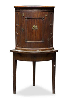 
	
		A North German mahogany corner cupboard on stand, early 19th century, of bow front form,...