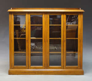 
	
		An Edwardian walnut and glazed bookcase, the top with three quarter gallery, above four...