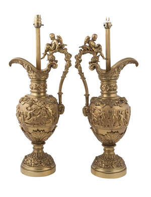 
	
		Two gilt-bronze ewer lamp bases, second half 20th century, the handles surmounted by...